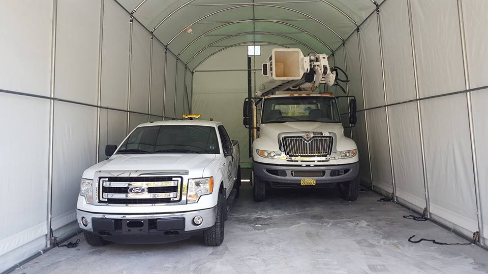 Two white trucks are parked in a garage.