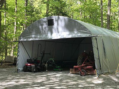 A large white tent is sitting in the middle of a forest.