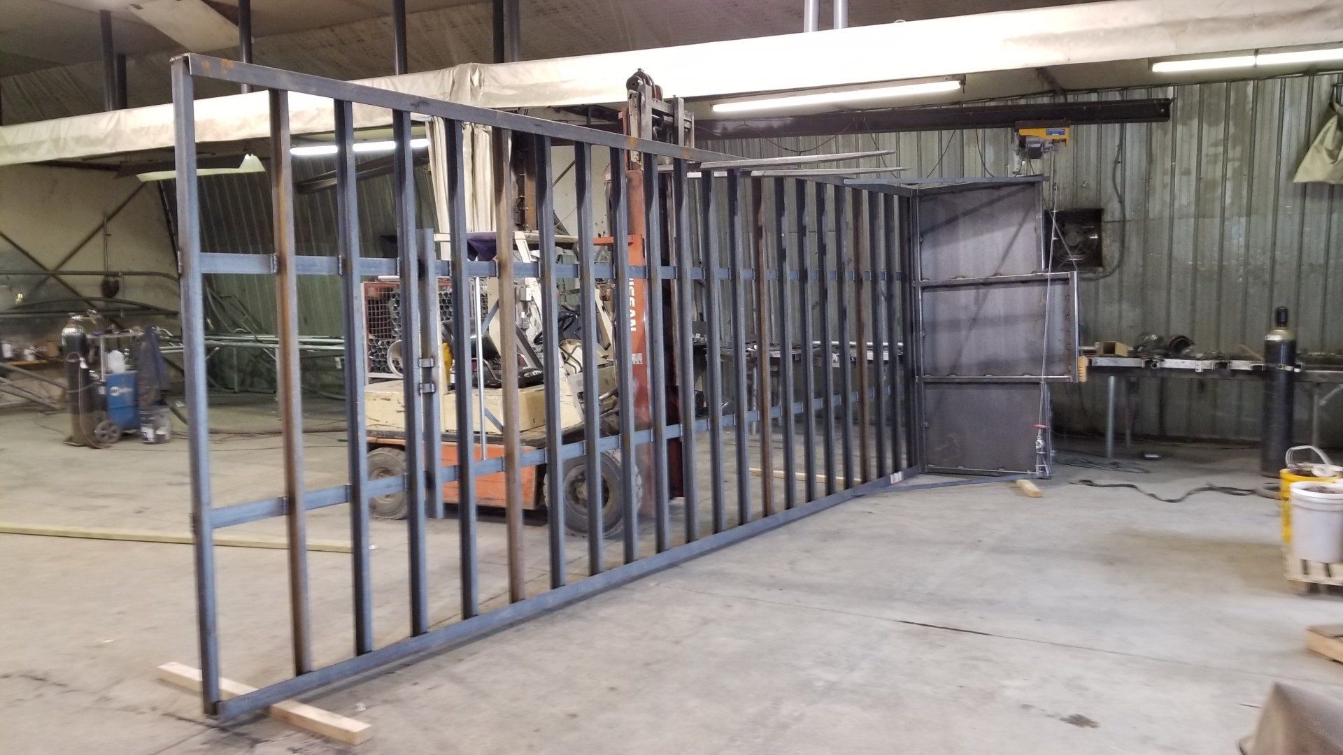 A large metal fence is being built in a factory.