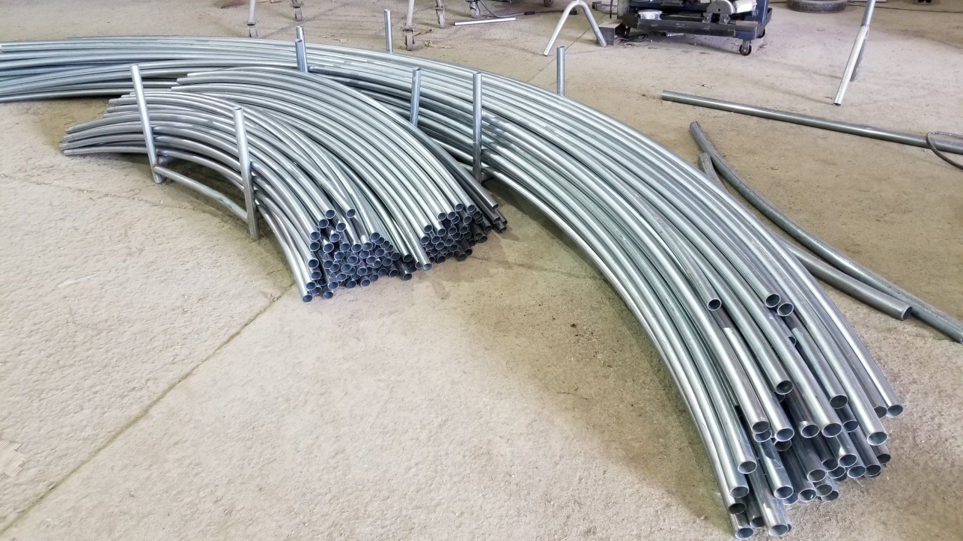 A bunch of metal pipes are stacked on top of each other on the floor.