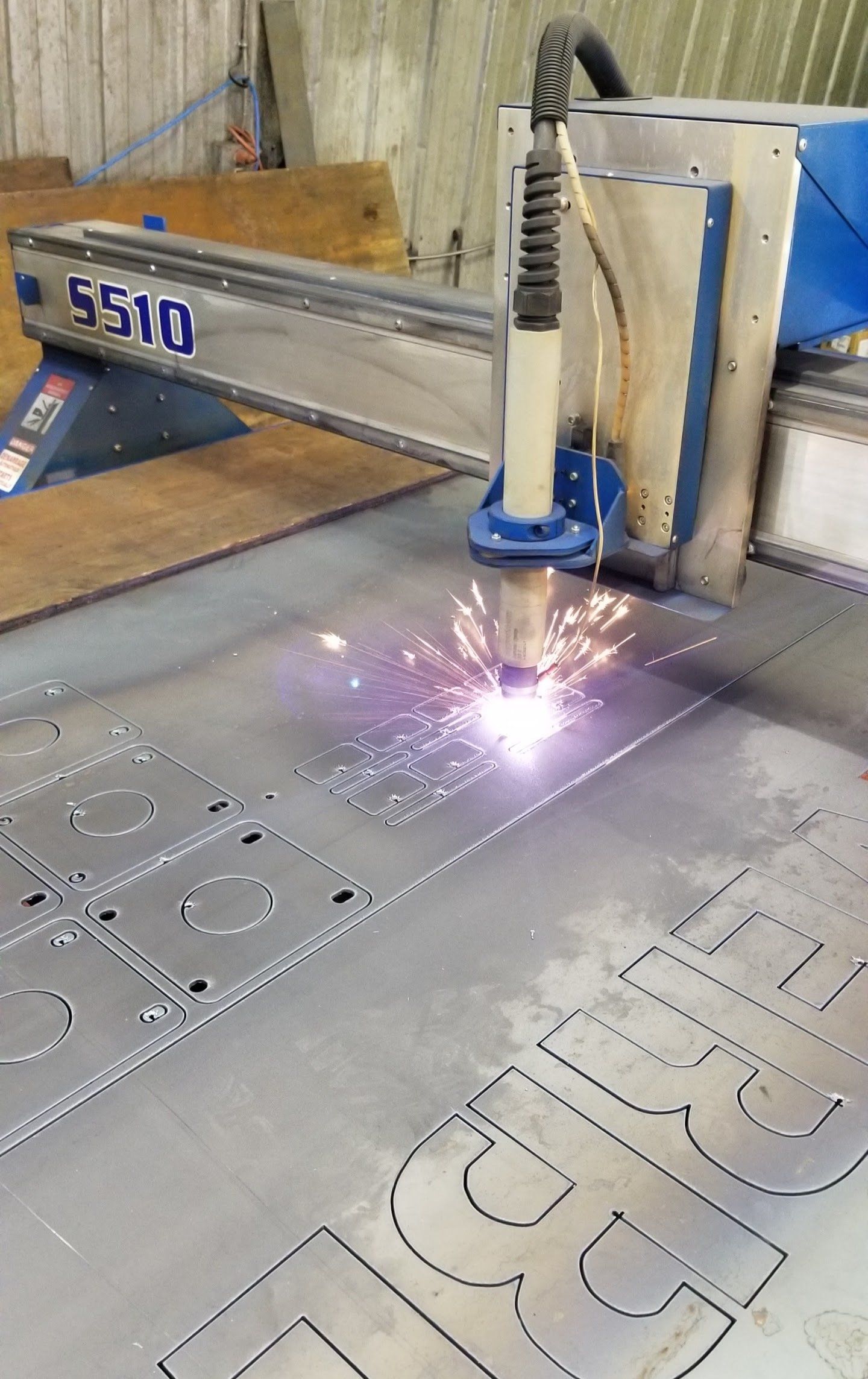 A machine is cutting a piece of metal with a flame coming out of it.