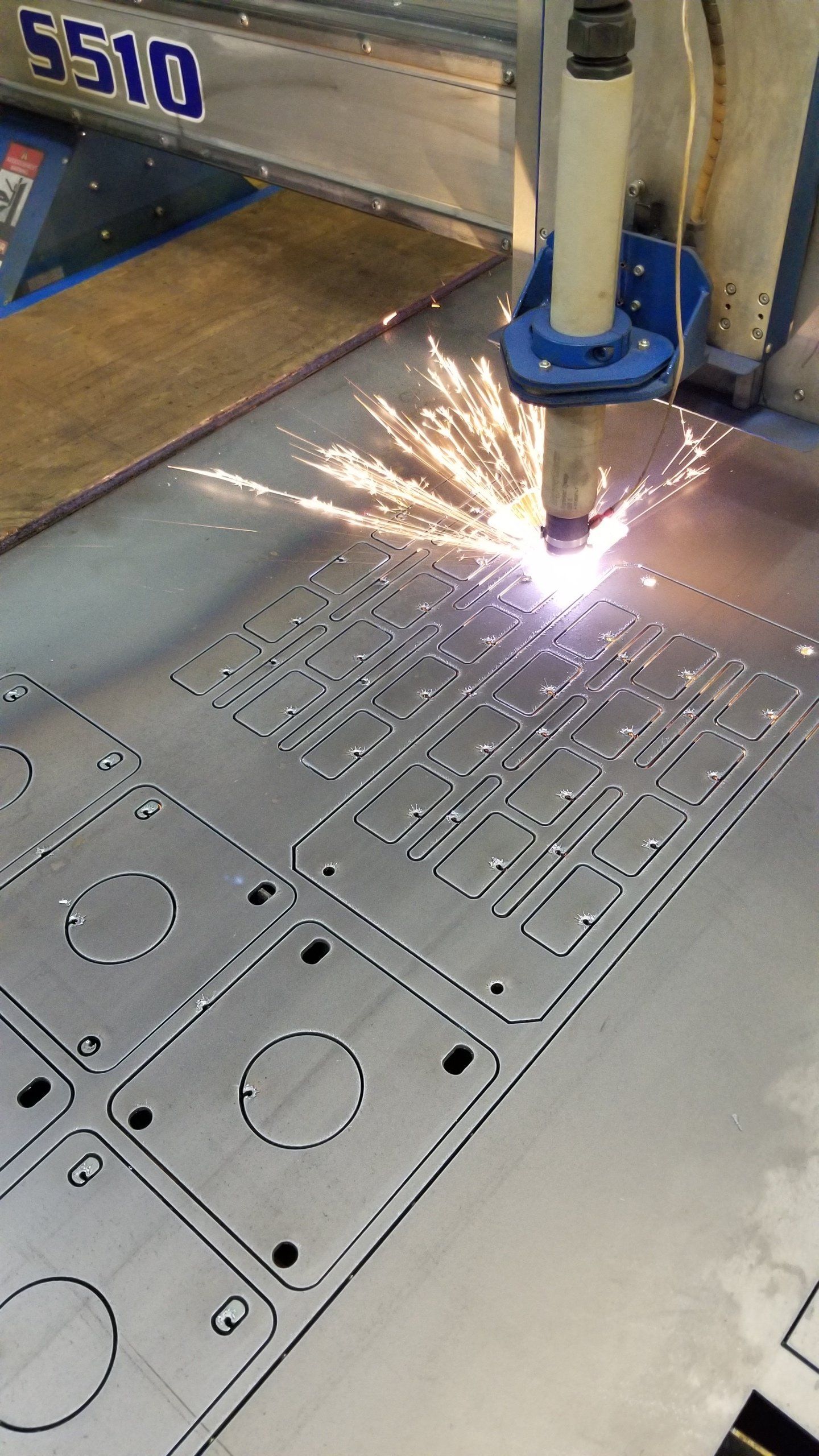 A machine is cutting a piece of metal with sparks coming out of it.