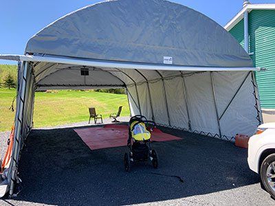 A stroller is sitting under a tent in a parking lot.