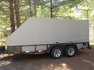 A trailer with a canopy on top of it is parked on a dirt road.