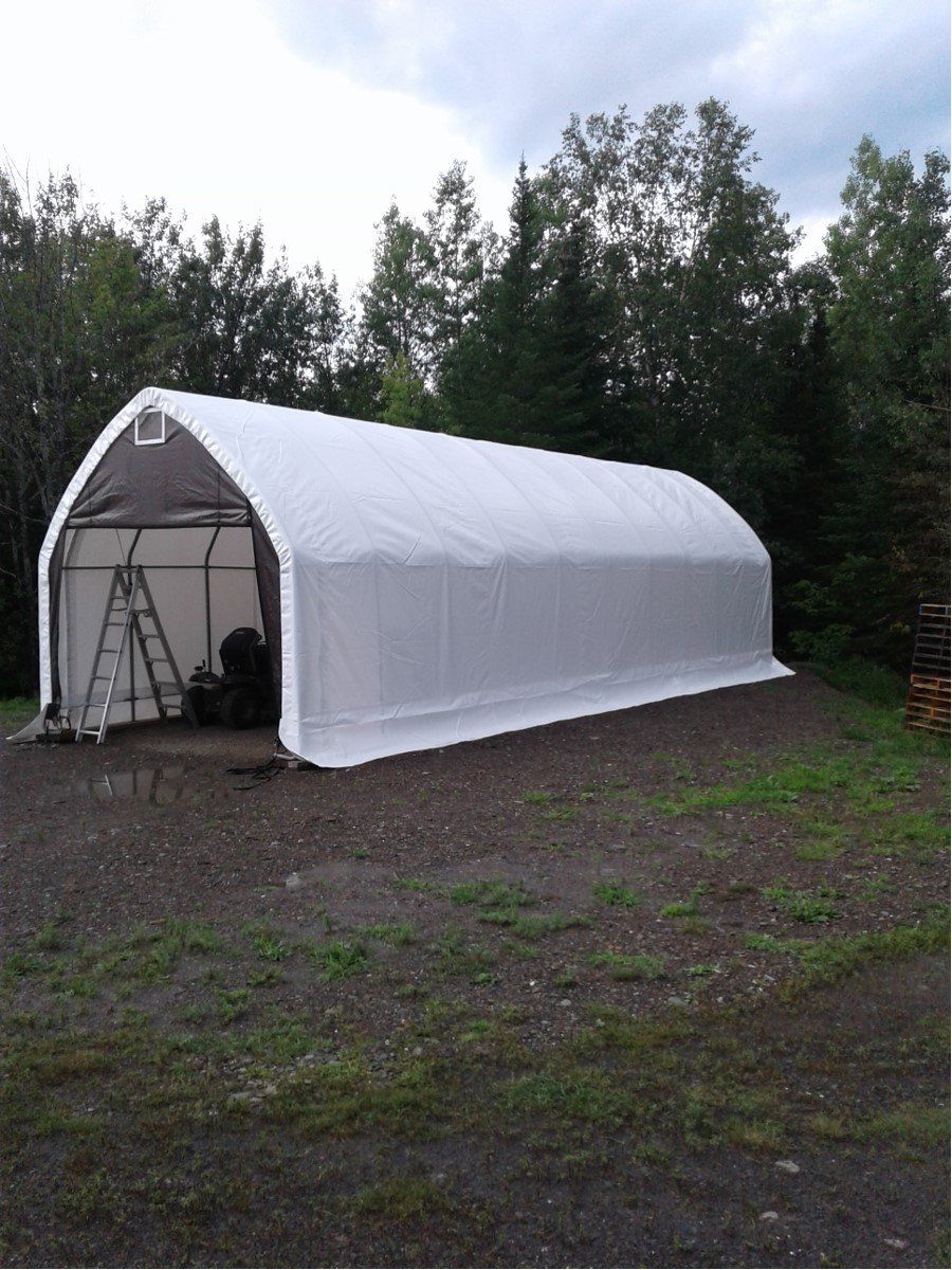 A large white tent is sitting in the middle of a dirt field.