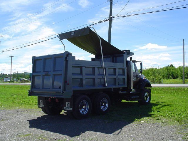 A dump truck is parked in a grassy field