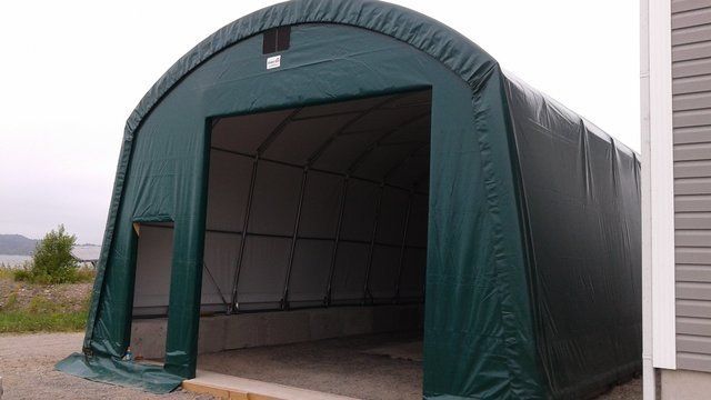 A green tent is sitting in front of a house.