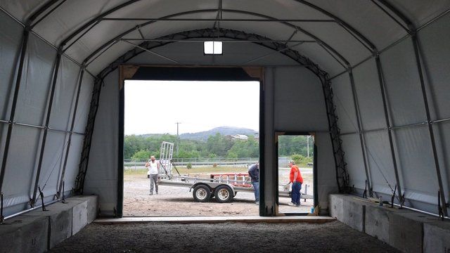 A trailer is parked inside of a building with the door open