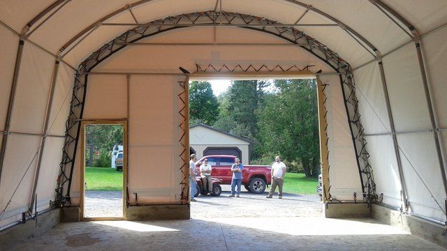 A red truck is parked in a garage under a tent