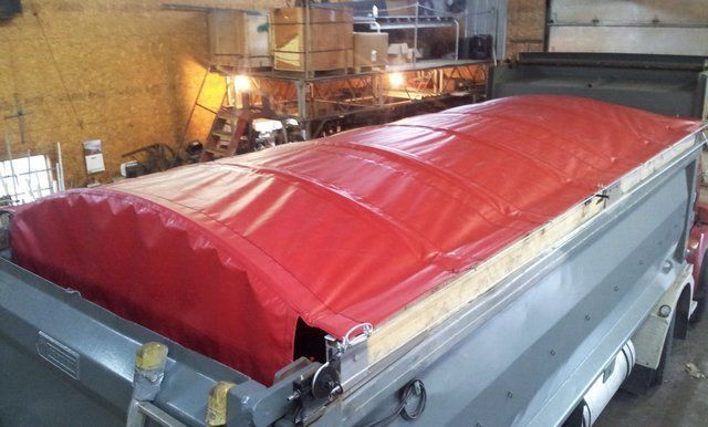 A red tarp is covering the roof of a trailer.