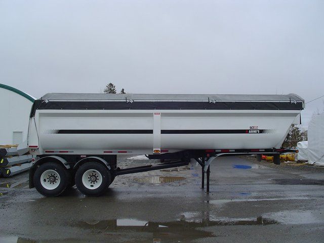 A white dump trailer is parked in a parking lot.