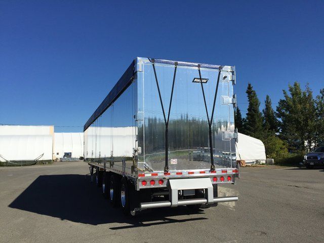 A silver semi truck is parked in a parking lot