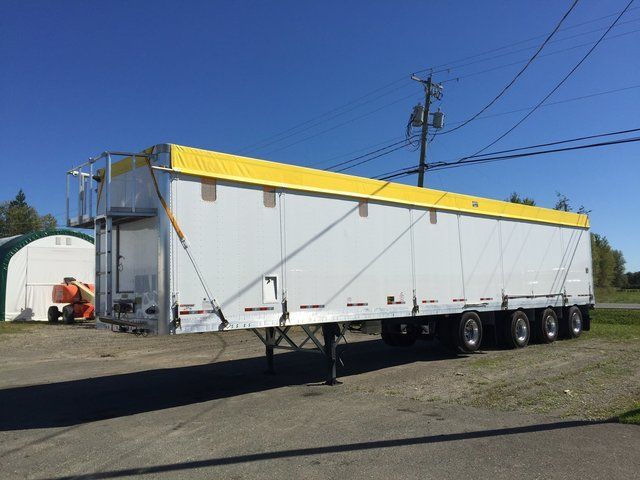 A white trailer with a yellow roof is parked in a parking lot.