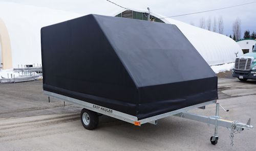 A black trailer is parked on the side of the road.