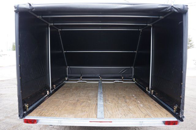 The back of a trailer with a black tarp on top of it.