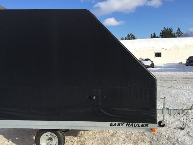 A black easy hauler trailer is parked in the snow