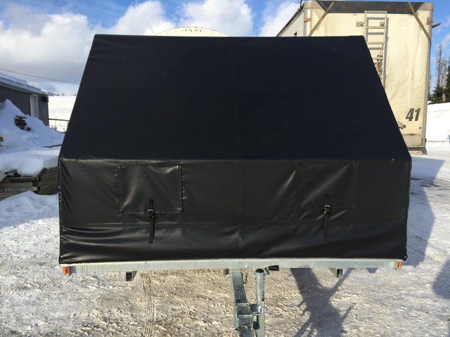 A black tent is sitting in the snow in front of a building with the number 41 on it.