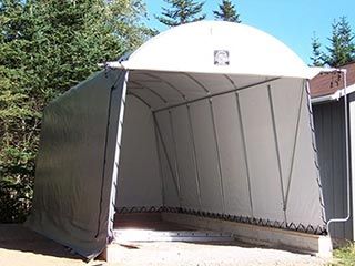 A large white tent is sitting in front of a house.