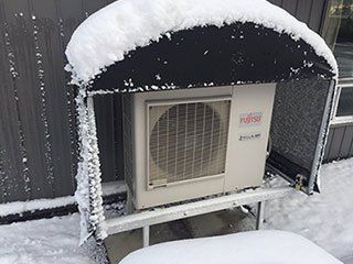 A fujitsu air conditioner is covered in snow