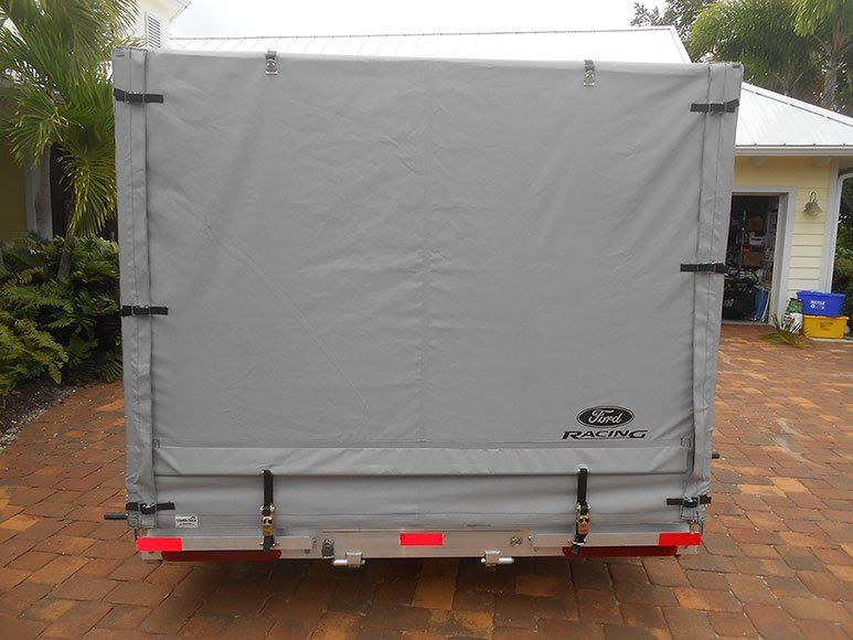 A trailer is parked on a brick driveway in front of a house.
