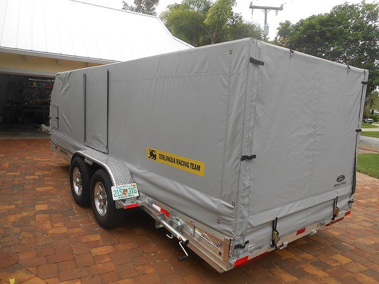 A trailer is parked on a brick driveway in front of a house.