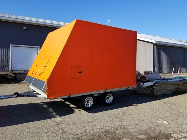An orange trailer is parked in front of a building