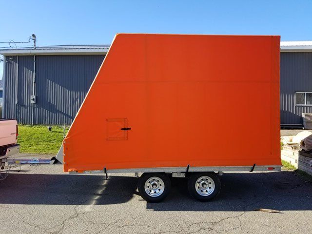 An orange trailer is parked in front of a building