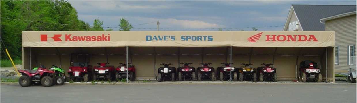 A row of atvs are parked in front of a kawasaki and honda store