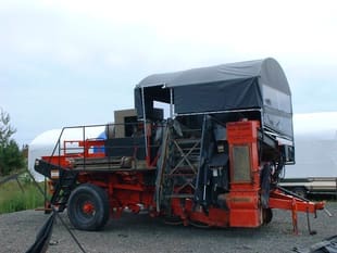 A red truck with a black canopy is parked on the side of the road.