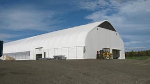 A large white building with a forklift parked in front of it.