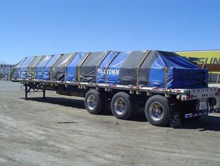 A row of semi trucks are parked in front of a building that says sun