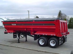 A red dump trailer is parked in a parking lot.