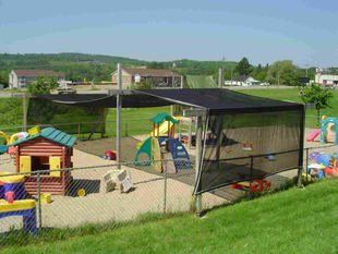 A playground with a fence surrounding it and a canopy over it.