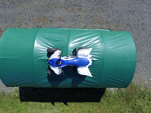 A blue and white motorcycle is wrapped in a green tarp