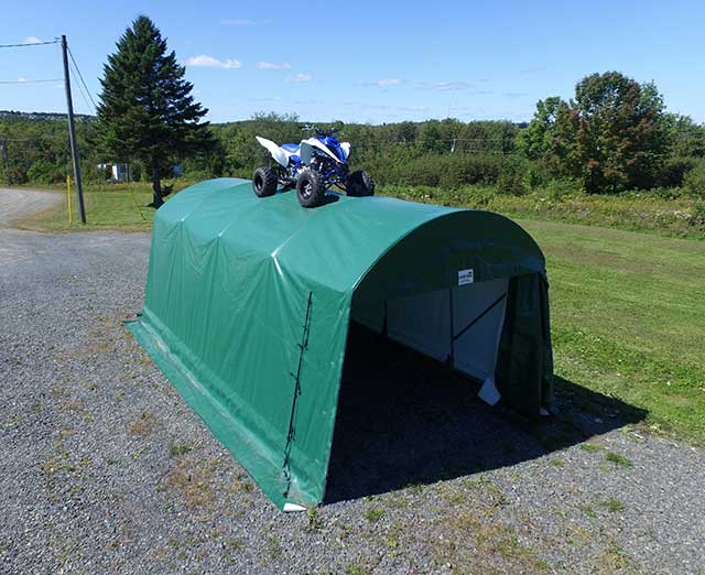 A blue and white atv is parked on top of a green tent