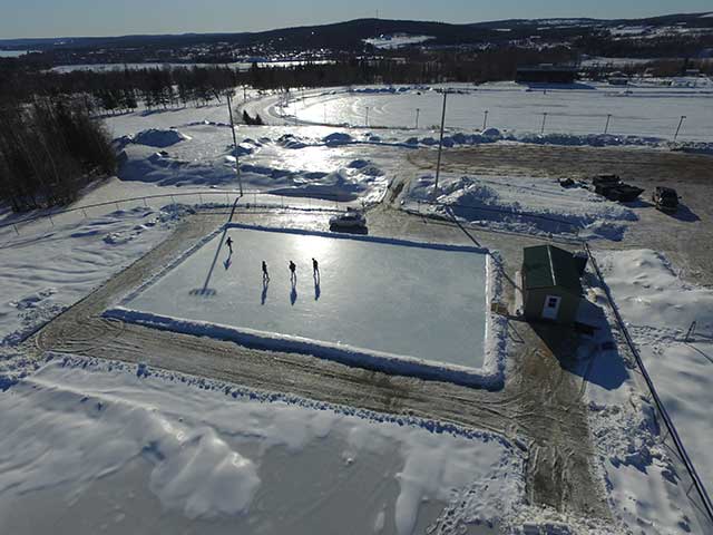 An aerial view of a ice rink in the middle of a snowy field.