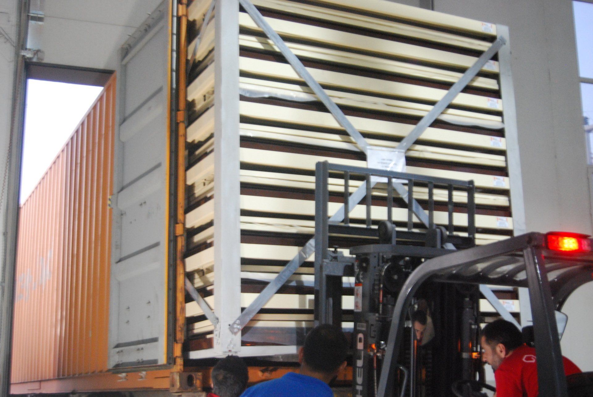 Forklift unloading large wooden crate from shipping container. Cover-Tech Portable Containers.