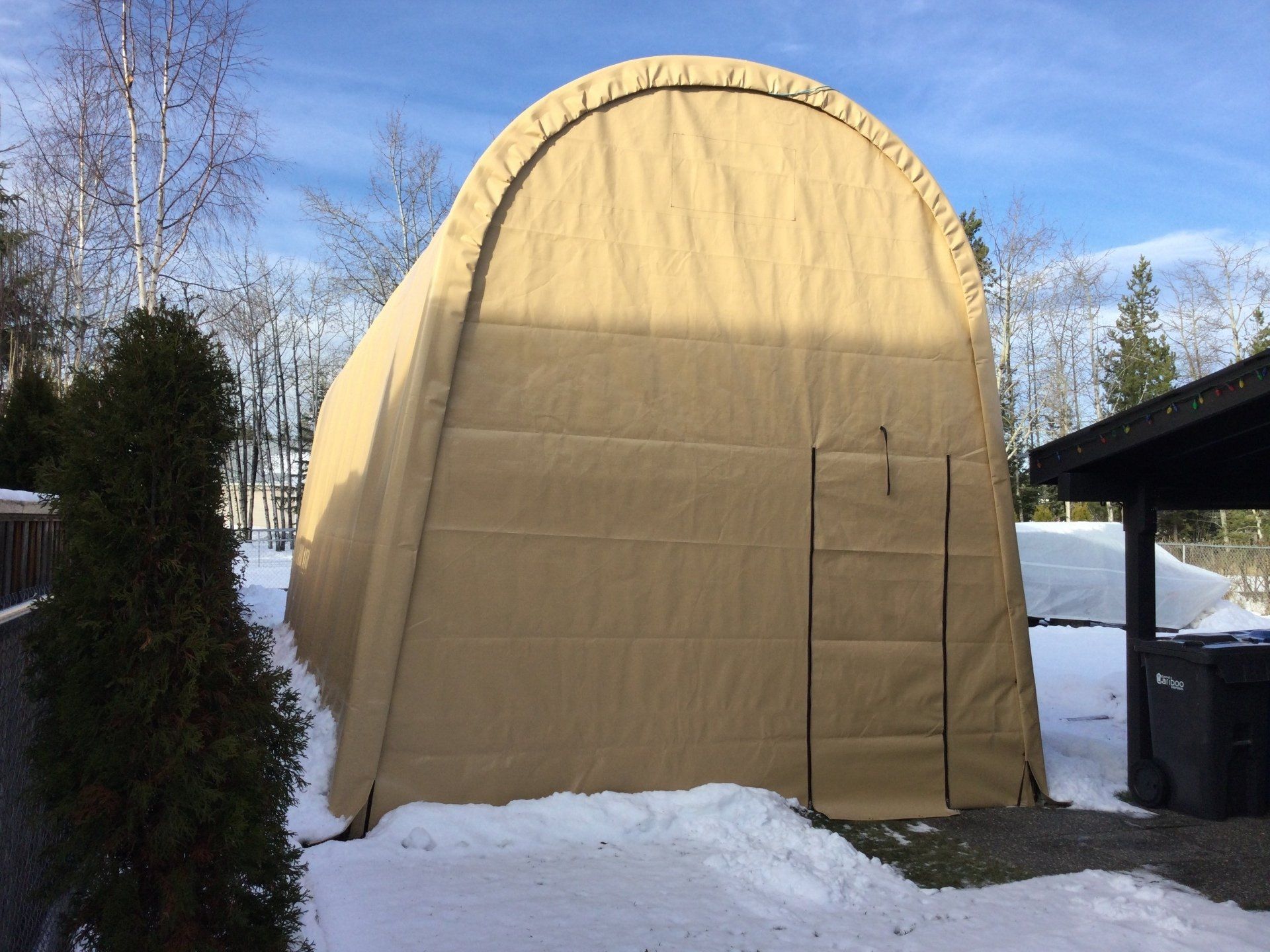 A large tent is sitting in the snow in front of a house
