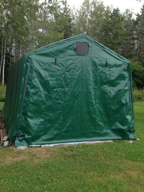 A green tent is sitting in the middle of a grassy field
