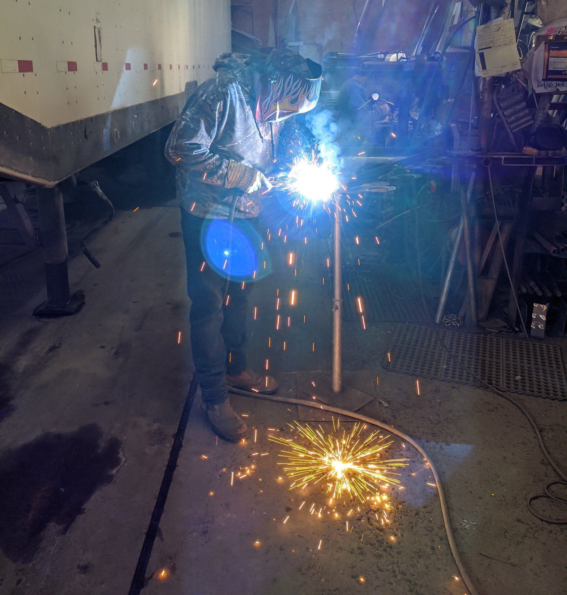 A man is welding a piece of metal in a garage.