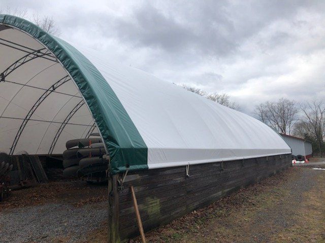 A large white tent with a green roof is sitting on top of a brick building.