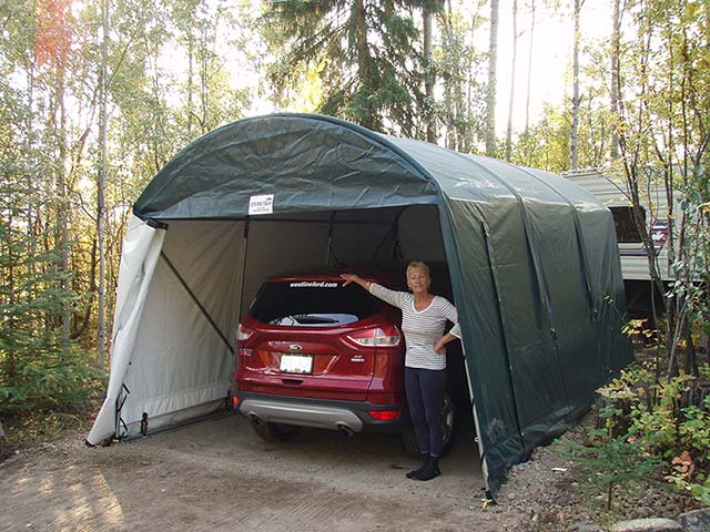 A woman is standing next to a car in a garage.