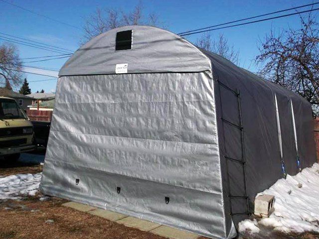 A large tent is sitting in the snow in front of a house.
