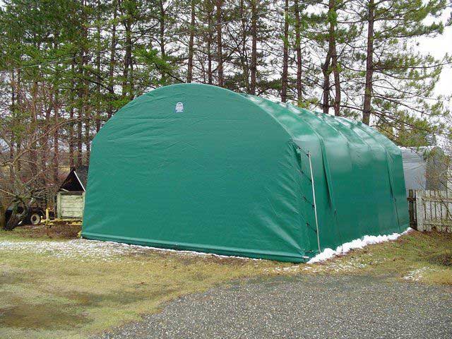 A green tent is sitting in the middle of a gravel road.