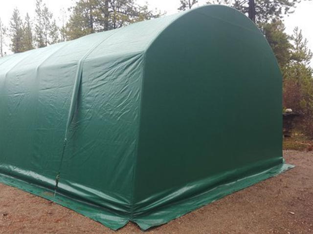 A green tent is sitting on top of a dirt field.