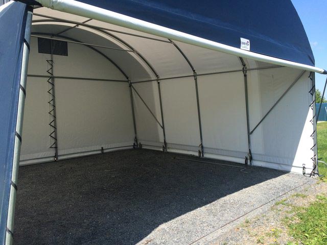 Blue and white arched storage shelter, open front, gravel floor. Cover-Tech Portable Garages.