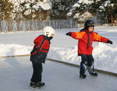 Two young boys are ice skating on a rink.