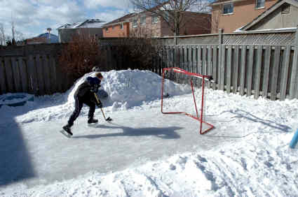 A young boy is playing ice hockey in a backyard.