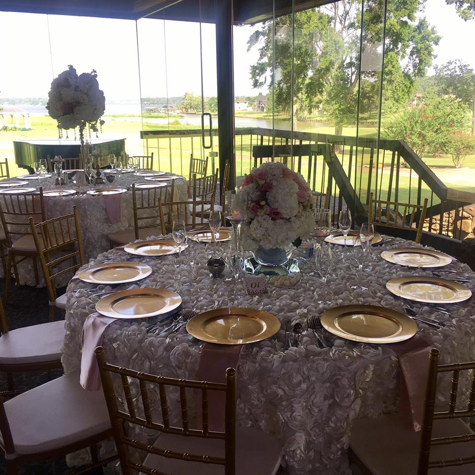 Wedding reception tables with gold chargers and floral centerpieces, set in a room with a view.