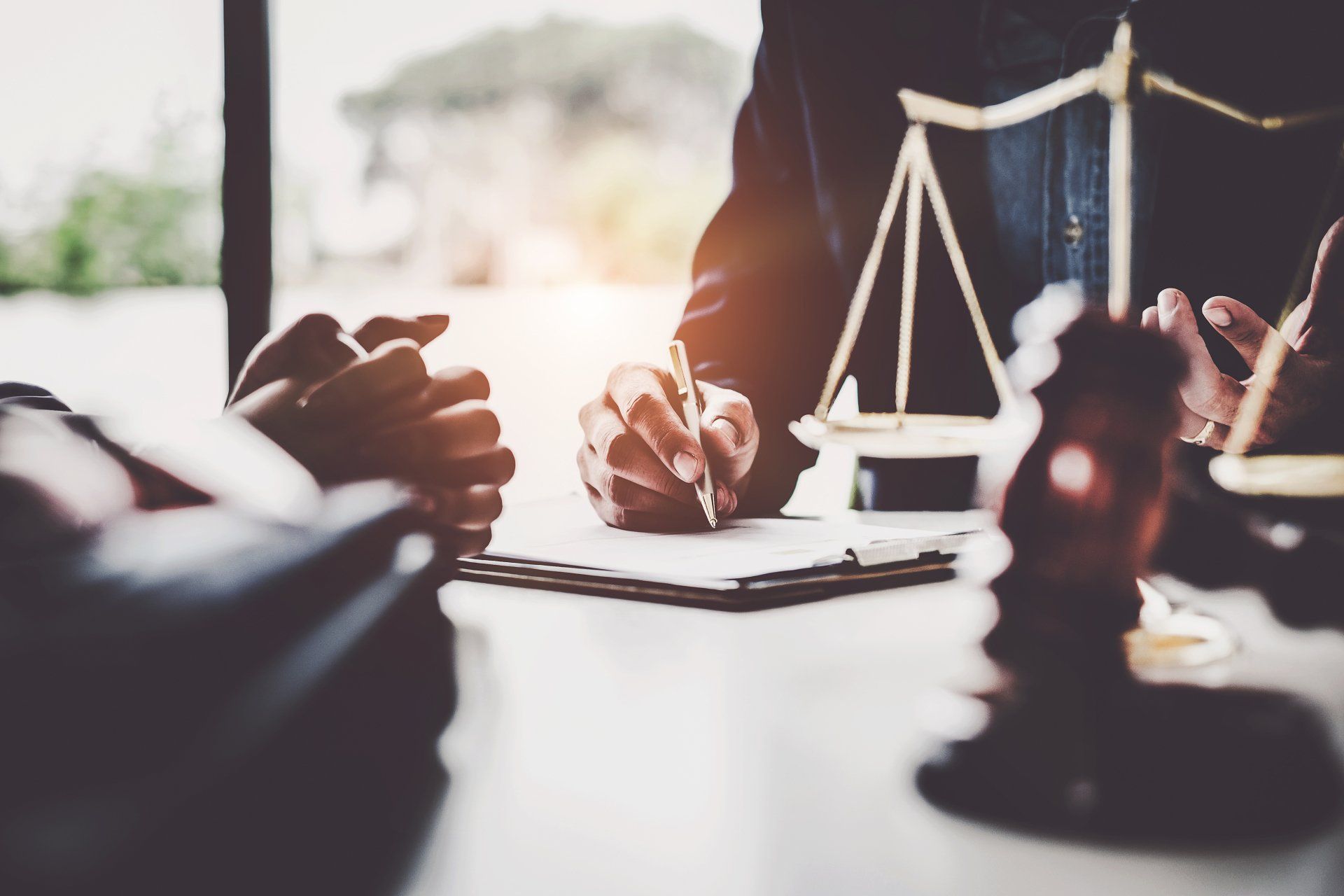 A lawyer is sitting at a table with a client and a scale of justice.